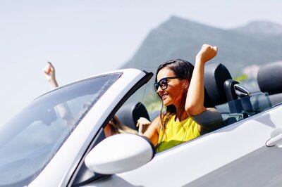 Eine Frau sitzt in einem Auto und freut sich über die Vorteile, die eine Auto Flatrate ihr zu bieten hat.