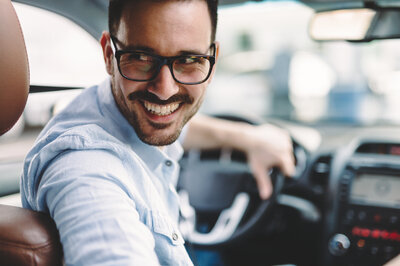 Ein Man sitzt im Auto und hat Fragen rund um den Autoverkauf in der Nähe.