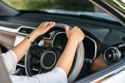 Eine Frau halt das Lenkrad eines Auto Abos in den Händen.